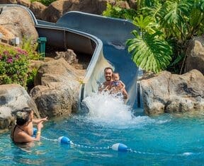 A man and woman are riding down the water slide.