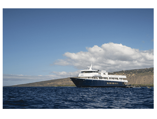 A private yacht cruising near a coastline in Hawaii under a clear sky.
